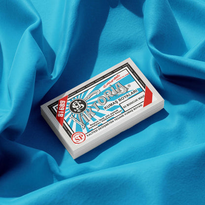 Pack of turquoise fabric dye placed on a vibrant blue fabric background